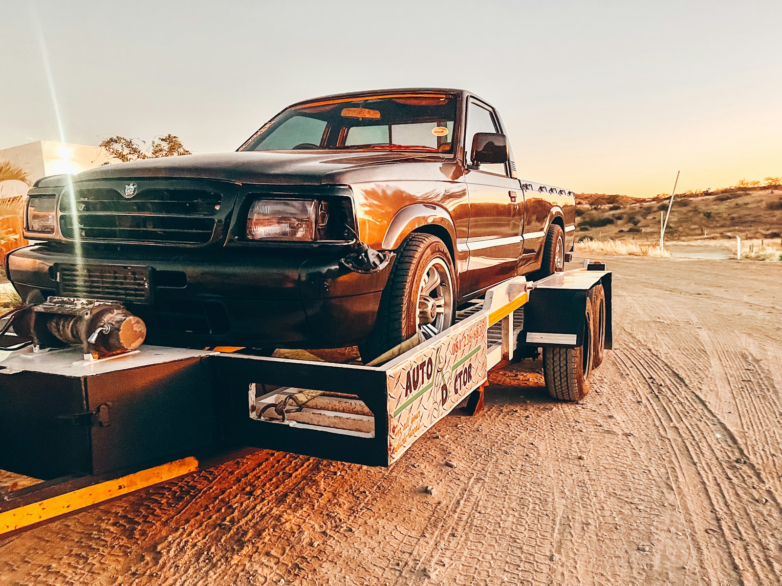Vehicle loaded on a tow truck in the desert at sunset